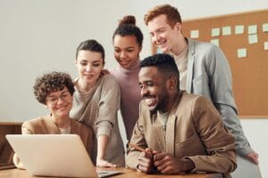 Group of accountants gather around a laptop. Happy and laughing